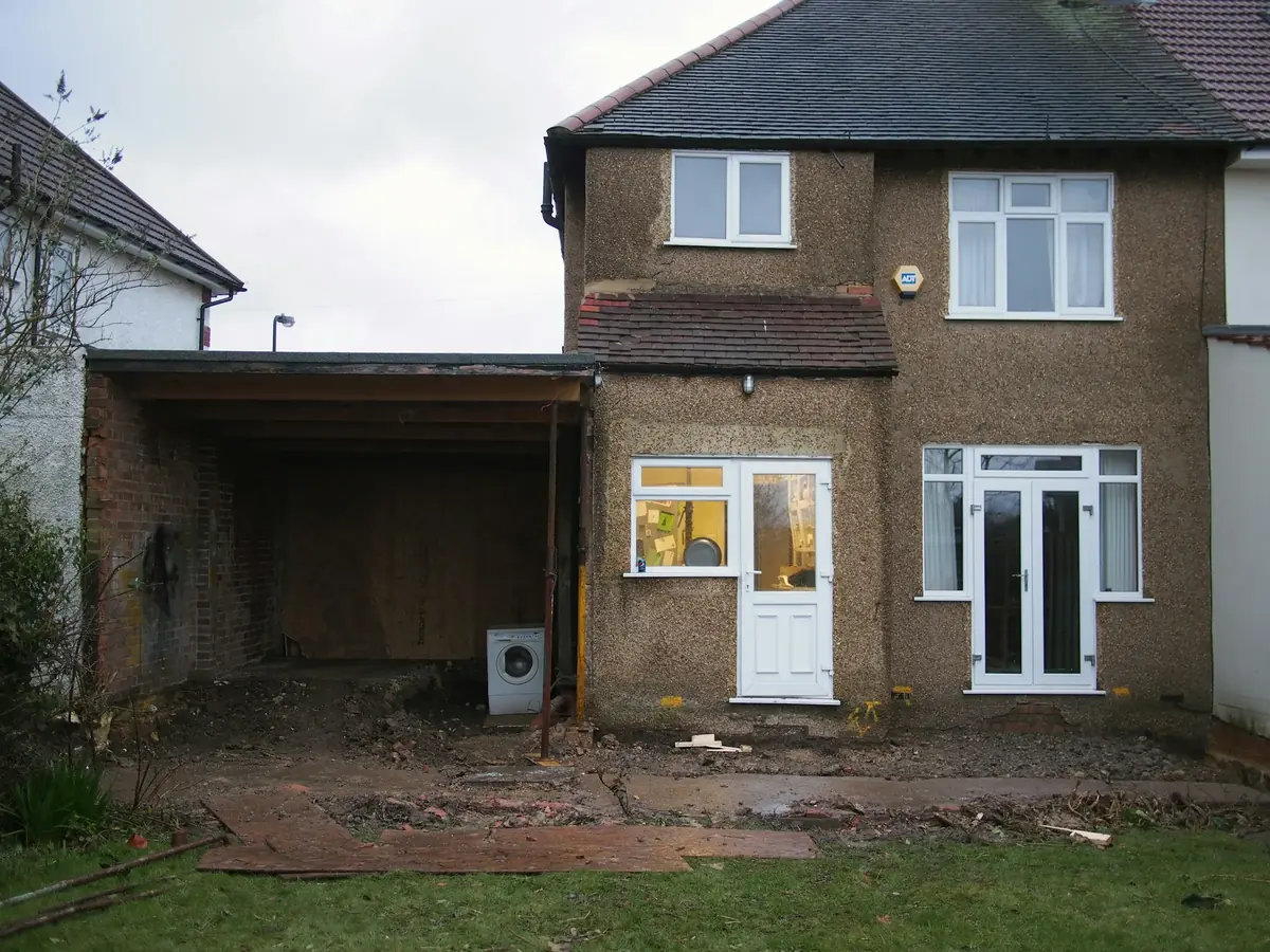 Before: the plain brick rear of the house, with an open carport on the left