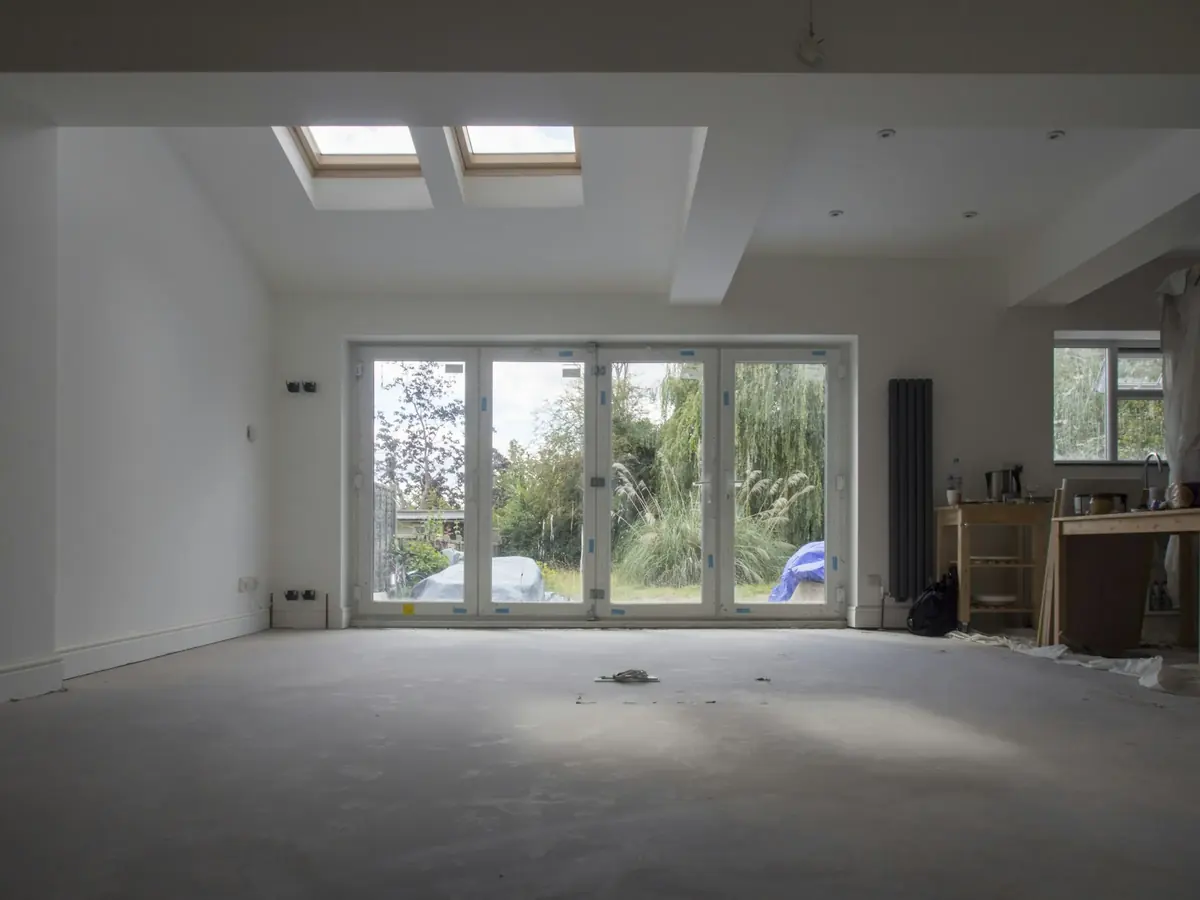 Finished: a bright empty room with roof lights in the ceiling and wide glazed doors to the garden