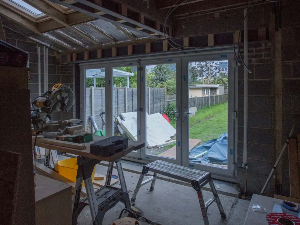 During the build: the same room as a bare shell, with exposed joists and tools on the floor