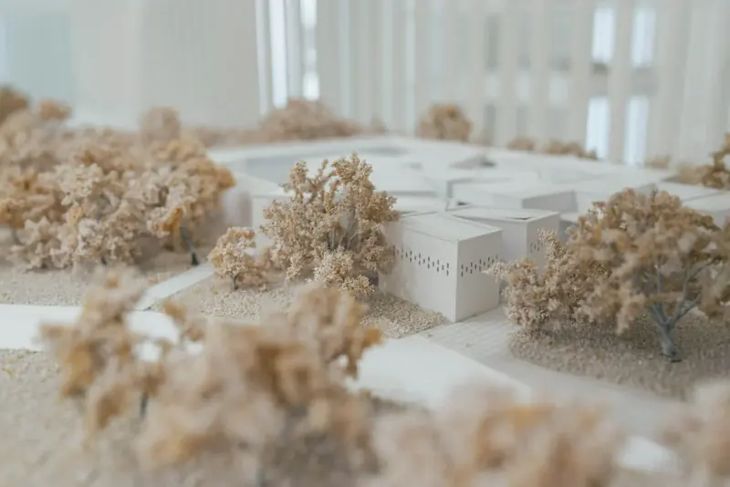 A white card architectural model of houses among model trees