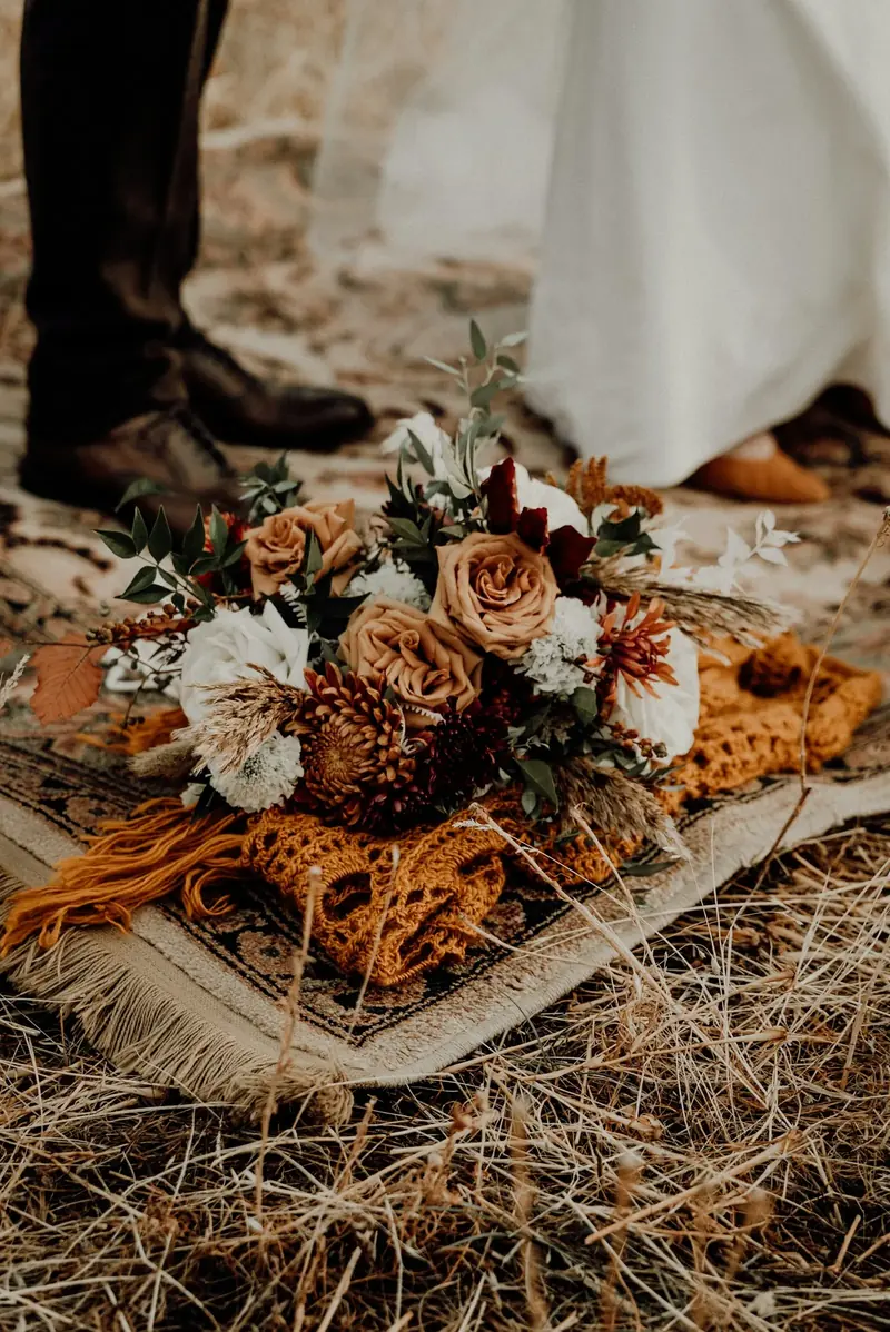 Bouquet of dried flowers in rust and cream, laid on fallen leaves