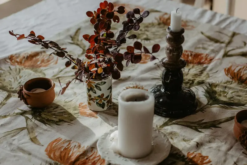 Table with a candlestick and a jar of autumn branches