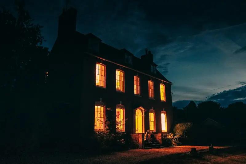 The side of the house at dusk, with the front steps lit