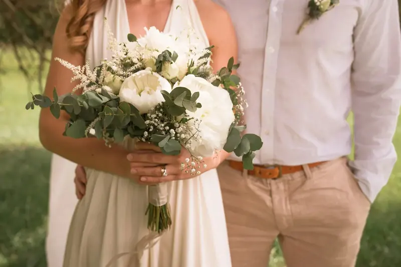 Bride holding a bouquet of white peonies and eucalyptus