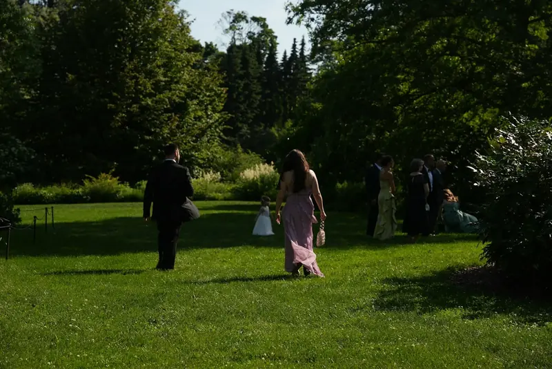 Guests in summer clothes walking across the lawn after the ceremony