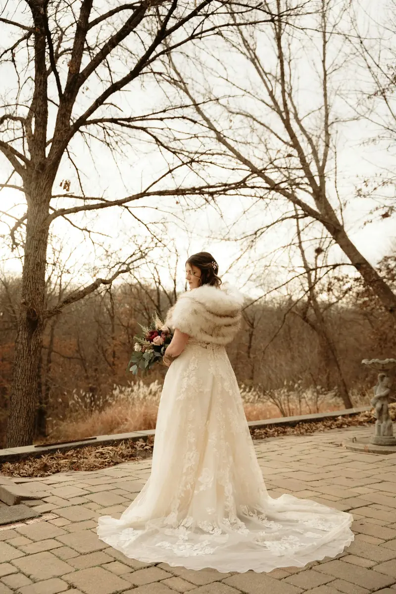 Bride in a fur wrap beneath bare winter trees