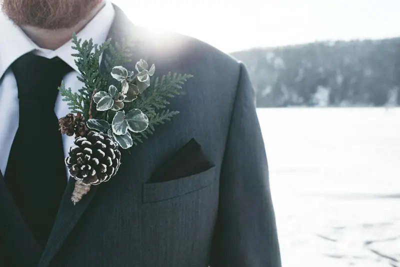 A buttonhole of pine and a small pinecone on a grey jacket